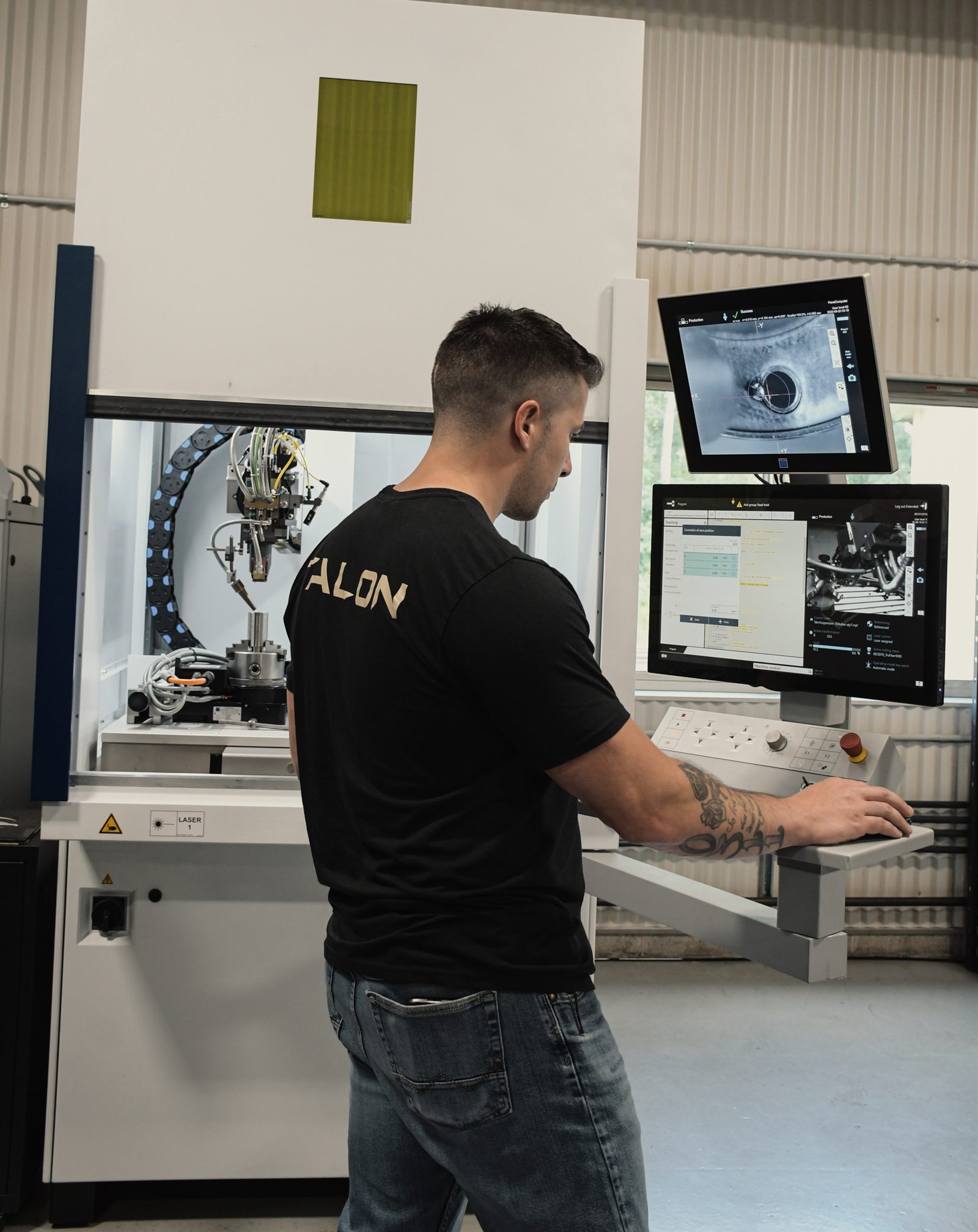 Talon technician at the laser weld cell console, weld head and camera view on the monitors