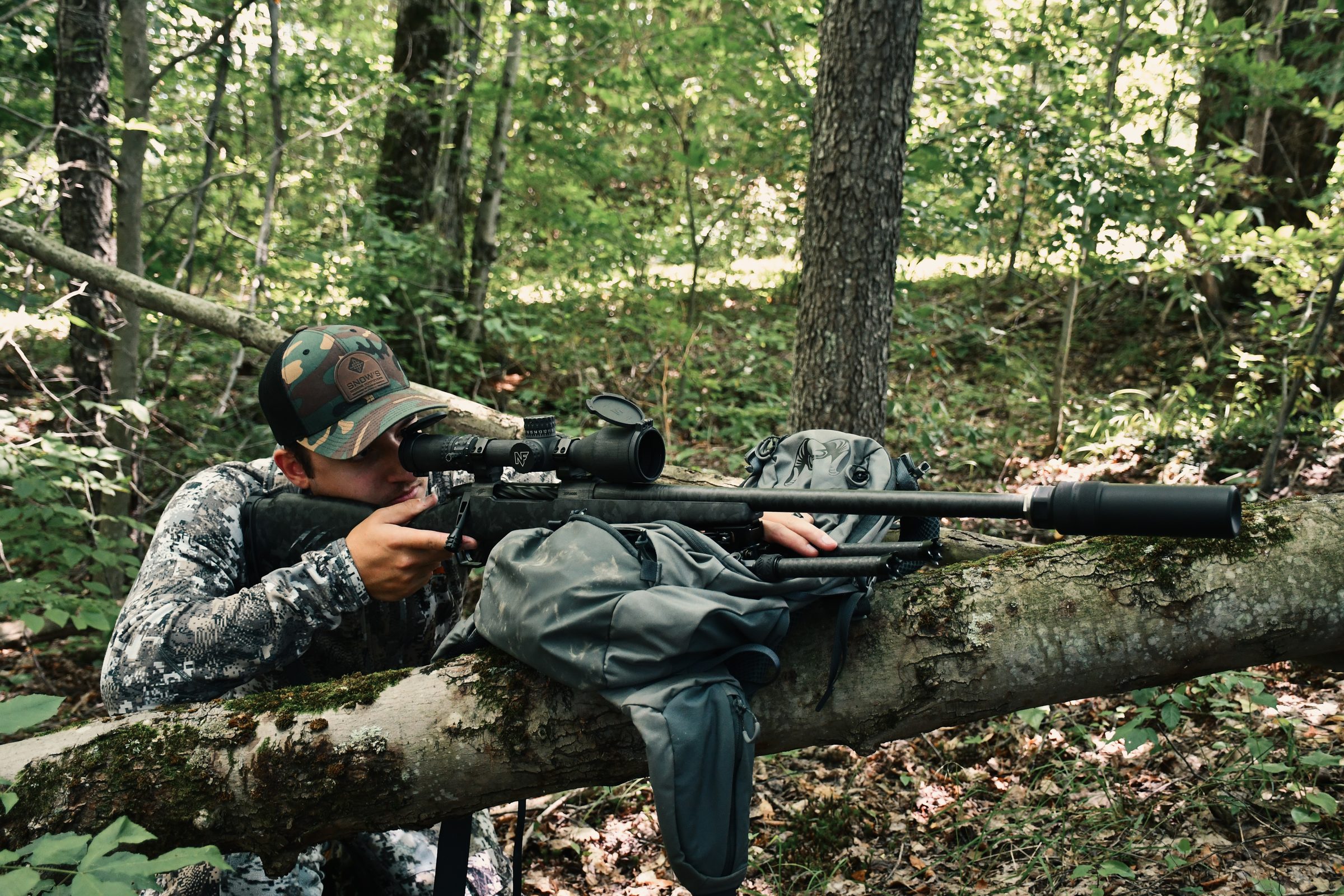 Peregrine on a bolt-action rifle, hunter prone on a log