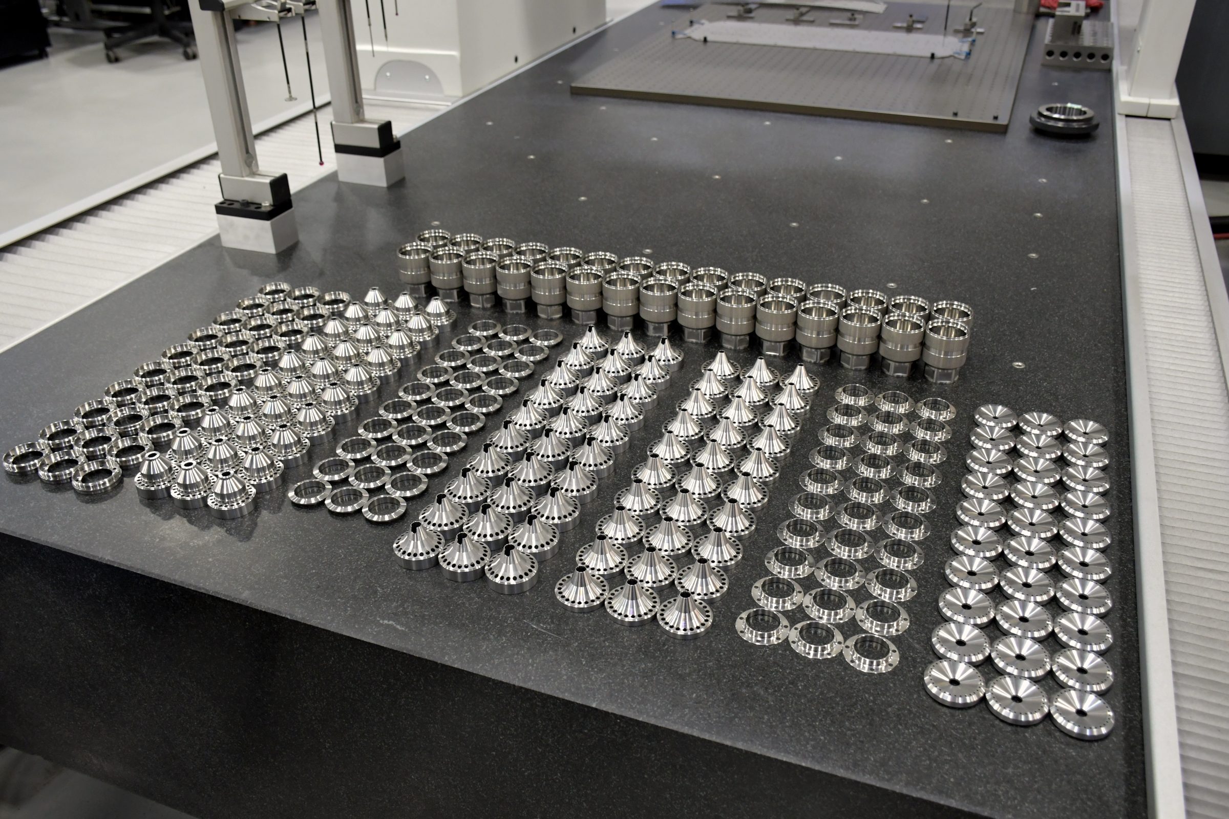 A full run of machined baffles, cores and end caps laid out on the granite inspection table